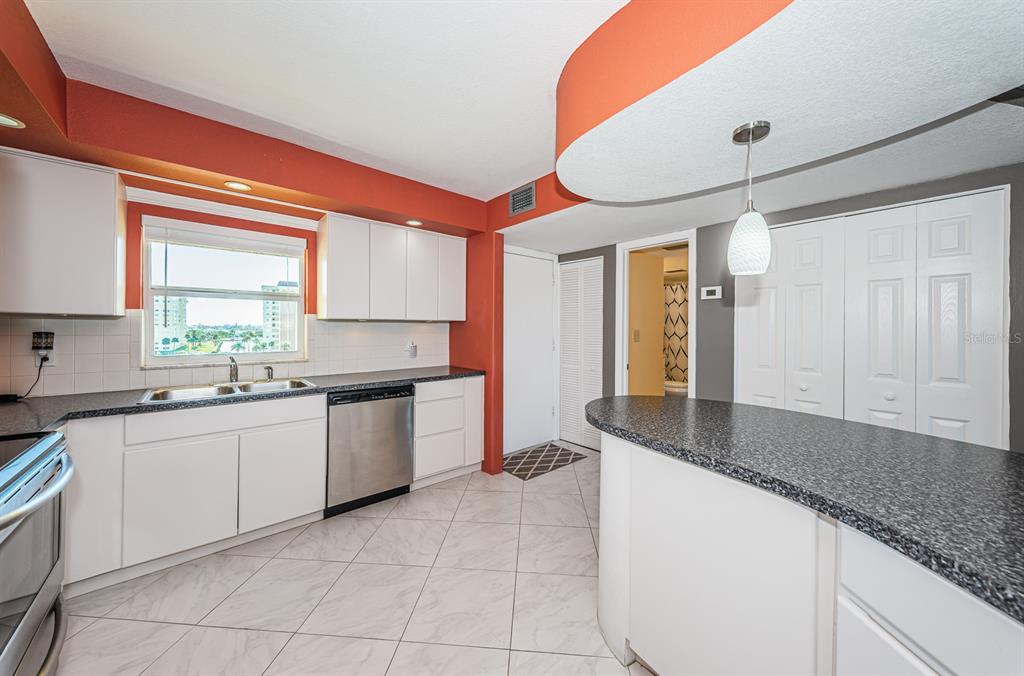 4725 Cove Circle, Unit 604 St. Petersburg, FL 33708 - Photo 11 of 53 a kitchen with granite countertop a sink and white cabinets