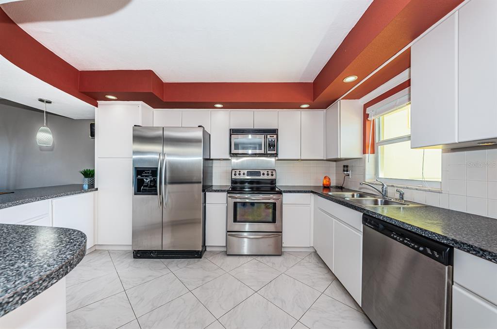4725 Cove Circle, Unit 604 St. Petersburg, FL 33708 - Photo 7 of 53 a kitchen with stainless steel appliances granite countertop a sink a stove and a refrigerator