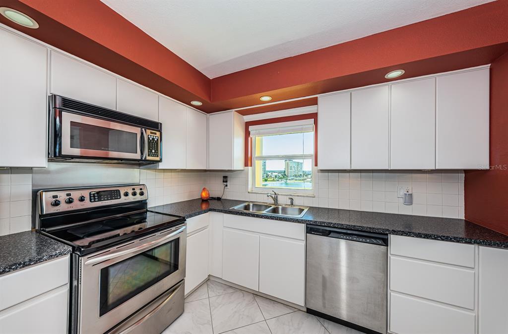 4725 Cove Circle, Unit 604 St. Petersburg, FL 33708 - Photo 8 of 53 a kitchen with stainless steel appliances granite countertop a sink a stove a microwave and cabinets
