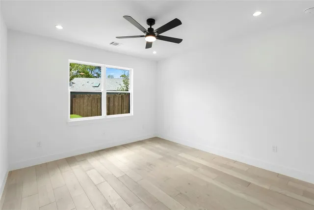an empty room with ceiling fan and windows