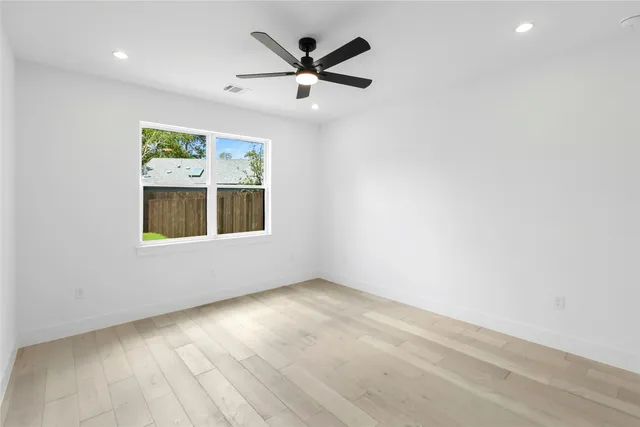 an empty room with ceiling fan and windows