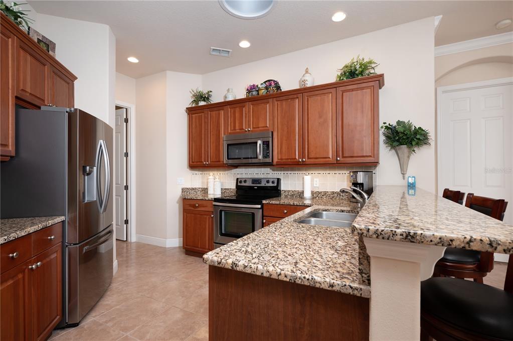 202 Lourdan Court DeBary, FL 32713 - Photo 15 of 38 a kitchen with kitchen island granite countertop stainless steel appliances a sink stove refrigerator and cabinets