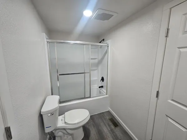 a bathroom with a granite countertop toilet a sink and shower