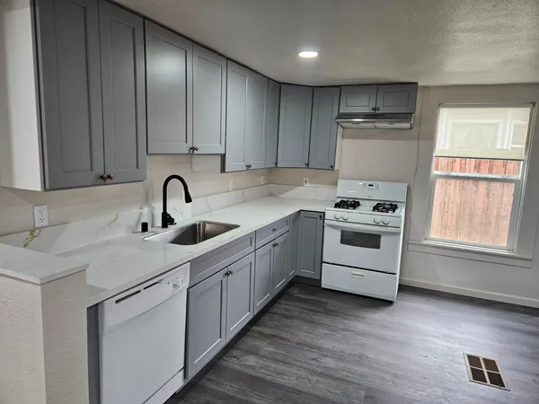 a kitchen with a sink white cabinets and appliances