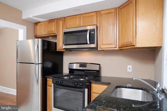 a kitchen with granite countertop a stove a refrigerator and a sink
