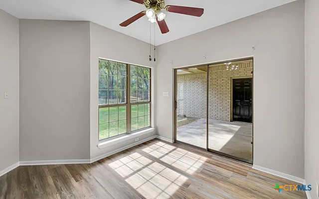 a view of a room with wooden floor fan and windows