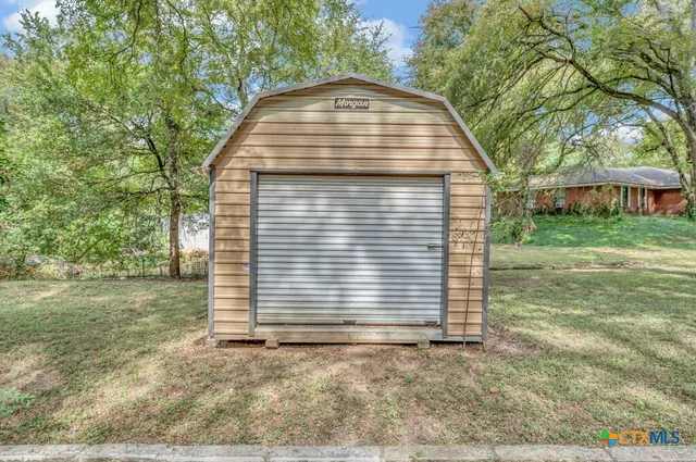 a view of a house with a yard and large tree