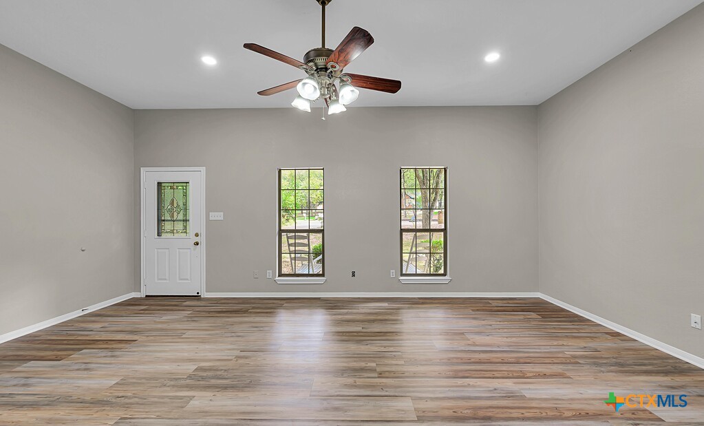 3900 Fox Ridge Road Lorena, TX 76655 - Photo 6 of 35 an empty room with wooden floor chandelier fan and windows