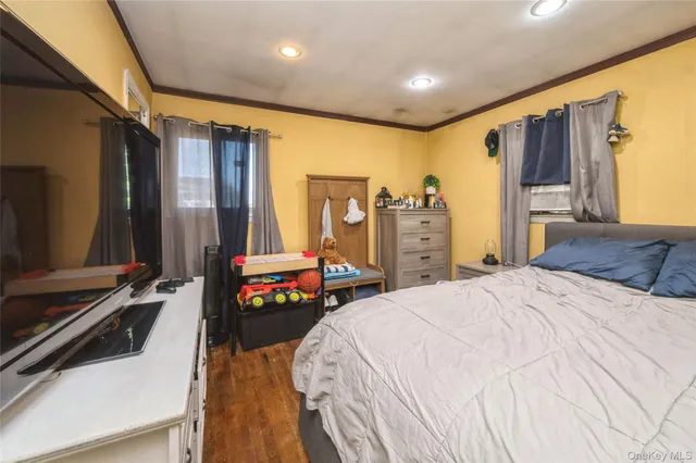a bedroom with a bed and a flat tv screen on dresser