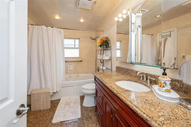 a bathroom with a granite countertop sink a toilet a mirror and shower
