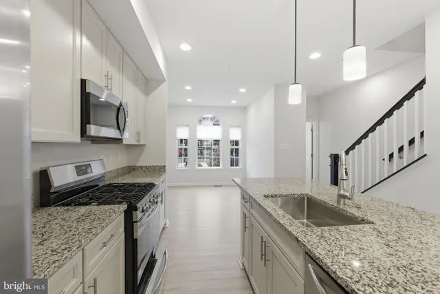 a kitchen with stainless steel appliances granite countertop a sink a stove oven a counter top space and cabinets