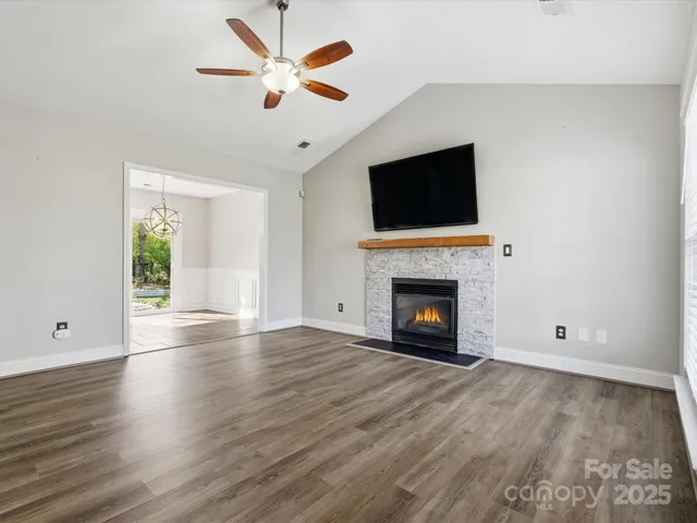 a view of an empty room with wooden floor fireplace and a window
