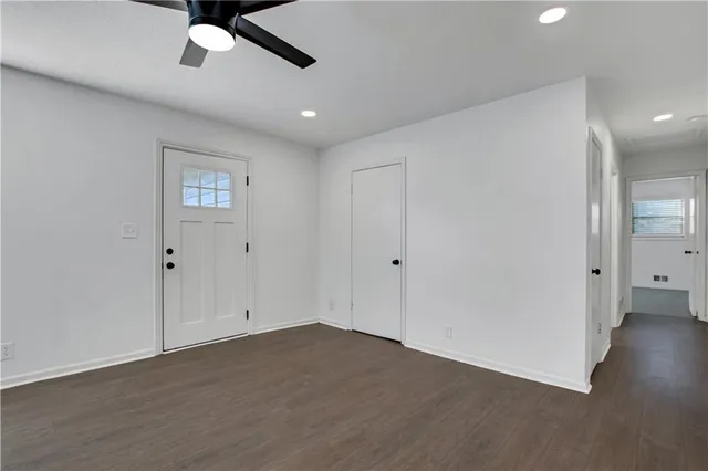 an empty room with wooden floor and ceiling fan