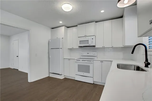 a kitchen with stainless steel appliances white cabinets and wooden floor