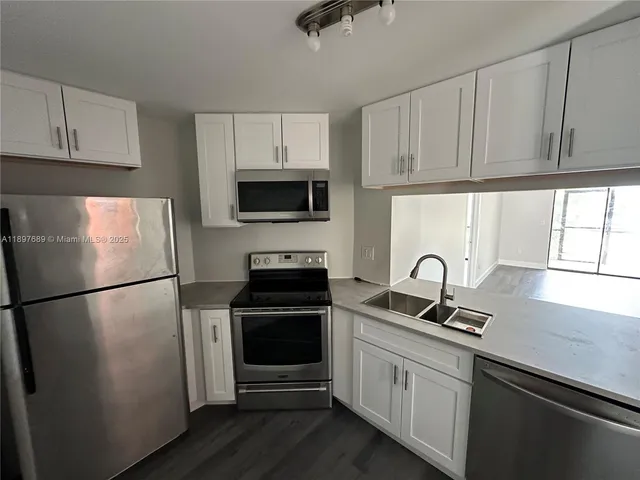 a kitchen with a refrigerator sink and cabinets
