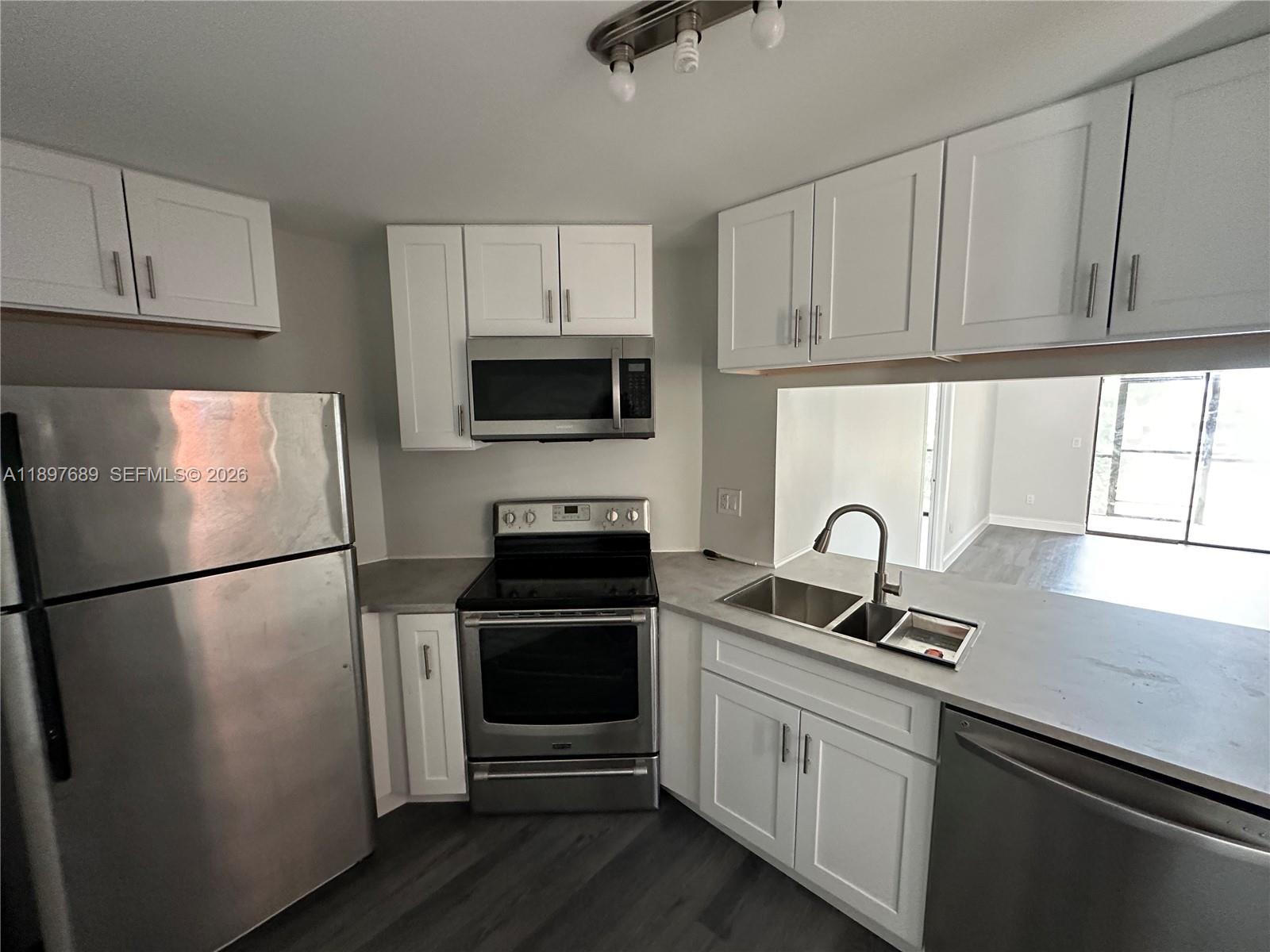 855 Northeast 209th Street, Unit 10334 Miami, FL 33179 - Photo 2 of 38 a kitchen with a refrigerator sink and cabinets