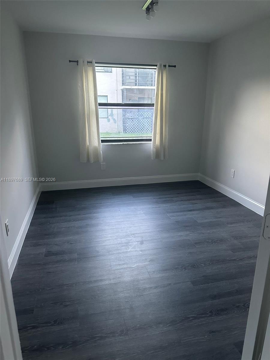 855 Northeast 209th Street, Unit 10334 Miami, FL 33179 - Photo 6 of 38 an empty room with wooden floor and windows