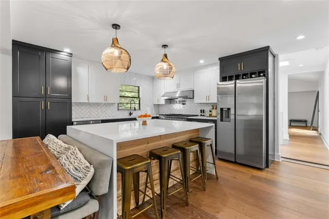 a kitchen with stainless steel appliances granite countertop a sink a stove a refrigerator cabinets and chairs