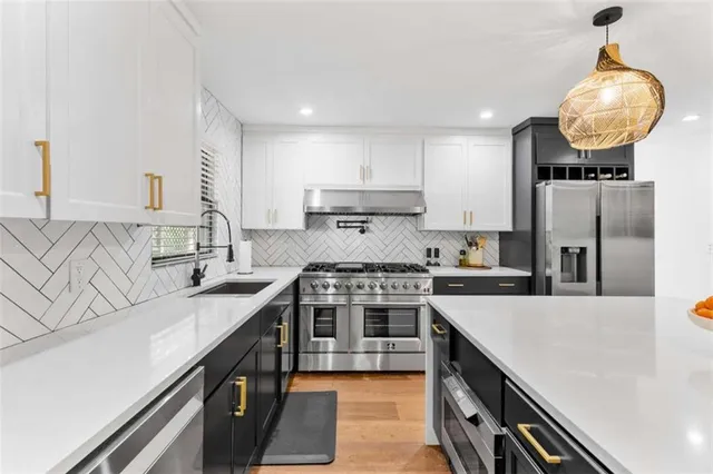 a kitchen with stainless steel appliances granite countertop a sink a stove and a refrigerator