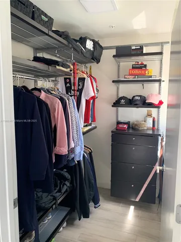 a view of walk in closet with clothes and shoes