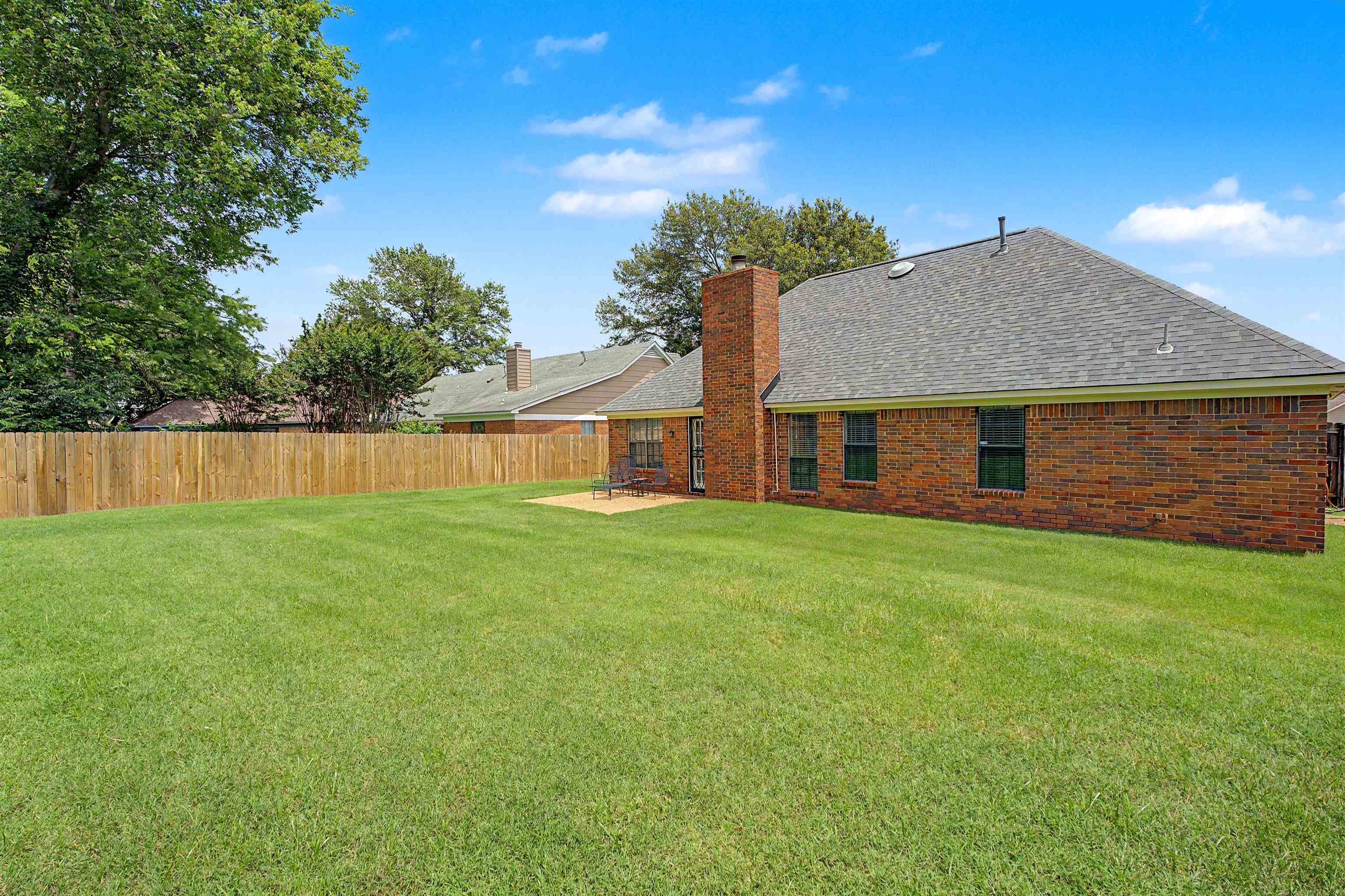 5127 Overview Ridge Memphis, TN 38141 - Photo 27 of 36 Expansive grass lawn featuring a wood privacy fence and a brick exterior with a pitched shingle roof