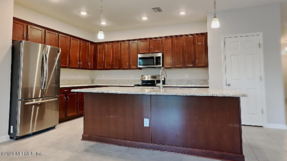 12032 Bridgehampton Road Jacksonville, FL 32218 - Photo 2 of 13 a kitchen with stainless steel appliances granite countertop a refrigerator a sink a stove a microwave and wooden cabinets