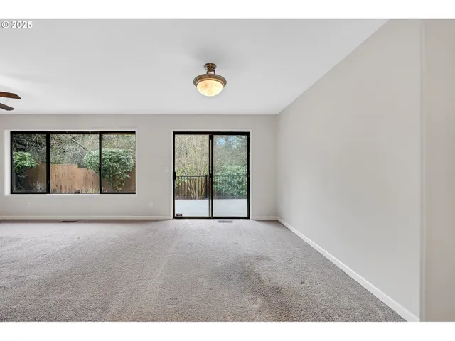 a view of a big room with windows and ceiling fan