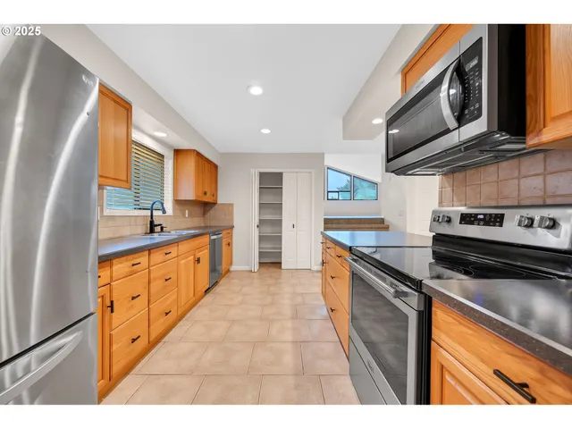 a large kitchen with stainless steel appliances granite countertop a stove a sink and a microwave