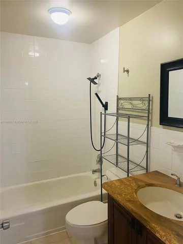 a bathroom with a granite countertop bathtub sink vanity mirror and toilet