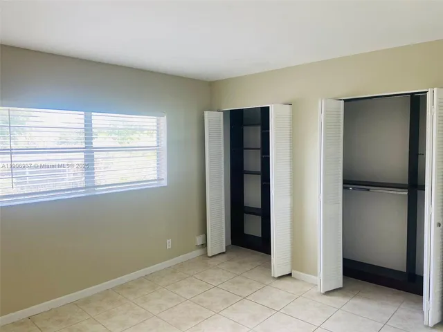 a view of an empty room with window and closet area