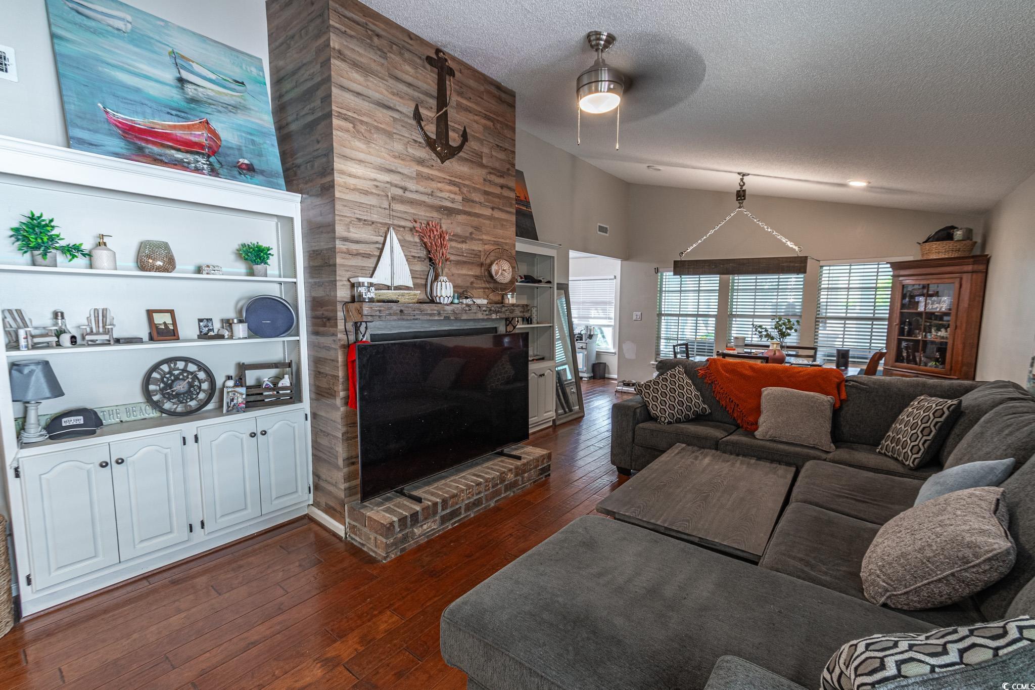 675 Mariner Avenue Murrells Inlet, SC 29576 - Photo 3 of 27 Living area with a fireplace, dark wood-type flooring, a textured ceiling, a ceiling fan, and lofted ceiling