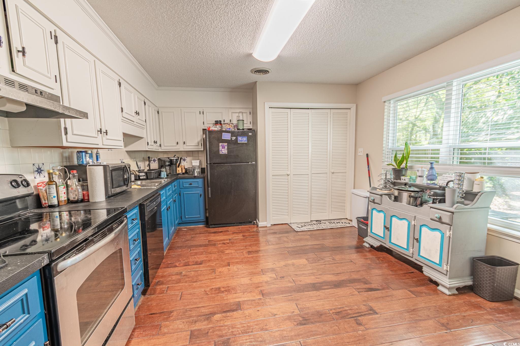 675 Mariner Avenue Murrells Inlet, SC 29576 - Photo 7 of 27 Kitchen featuring dark countertops, light wood-style floors, black appliances, and blue cabinets