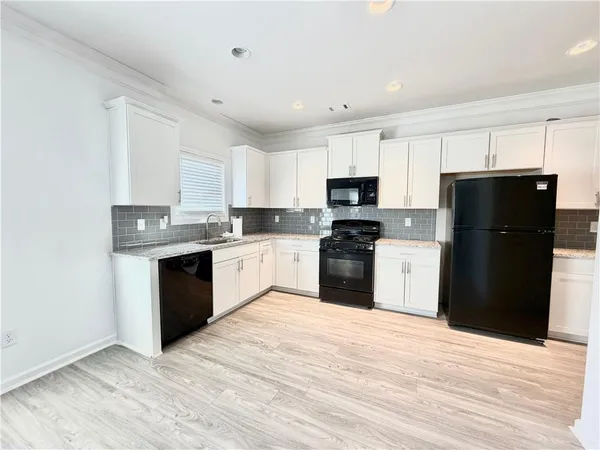 a kitchen with a refrigerator a stove top oven a sink and dishwasher with wooden floor