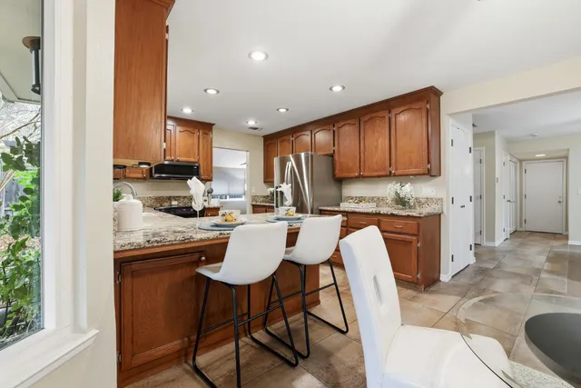 a view of a patio with table and chairs potted plants with floor to ceiling window and wooden fence