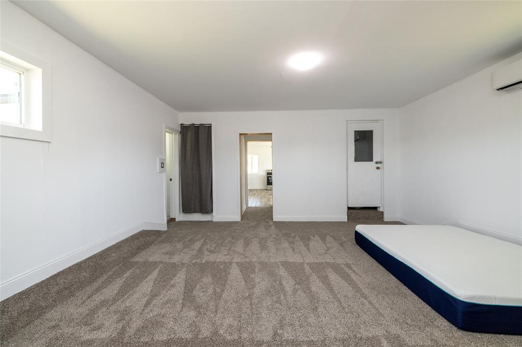 151 County Road 3699 Springtown, TX 76082 - Photo 19 of 35 Spacious room featuring new carpeting, crisp white walls, a recessed window, a wall-mounted mini-split unit, and an overhead flush-mount light fixture