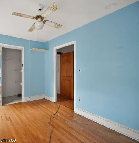 a view of a room with wooden floor and a ceiling fan
