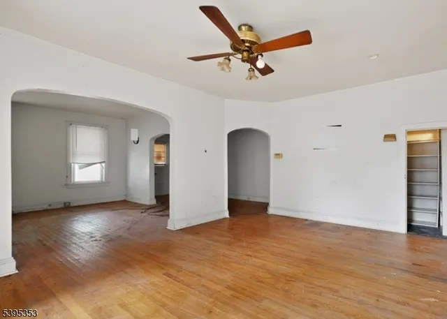 a view of empty room with wooden floor and ceiling fan
