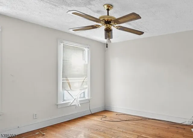 an empty room with wooden floor fan and windows