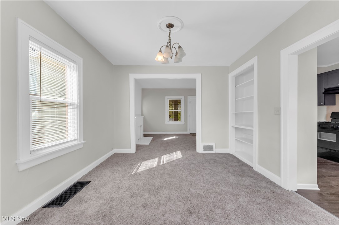 945 Nela View Road Cleveland Heights, OH 44112 - Photo 11 of 27 Unfurnished dining area featuring built in features, a chandelier, and carpet flooring