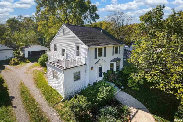 a aerial view of a house with yard and trees in the background