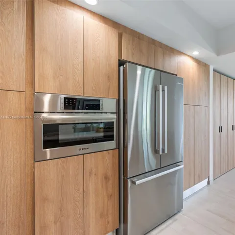 a large kitchen with stainless steel appliances a large counter top a stove a refrigerator and a sink