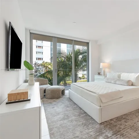 a bedroom with a large bed and a flat tv screen on dresser
