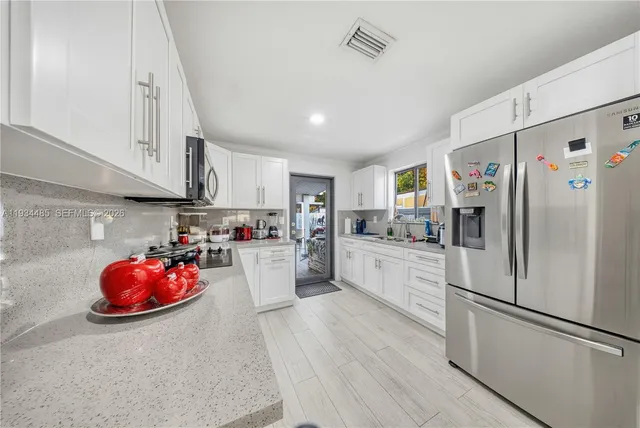 a kitchen with stainless steel appliances a refrigerator sink cabinets and wooden floor