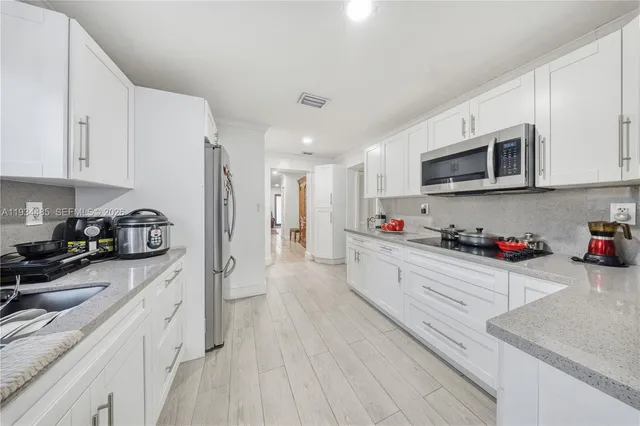 a large white kitchen with stainless steel appliances granite countertop lots of counter top space and cabinets