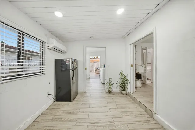 a hallway with wooden floor and a refrigerator
