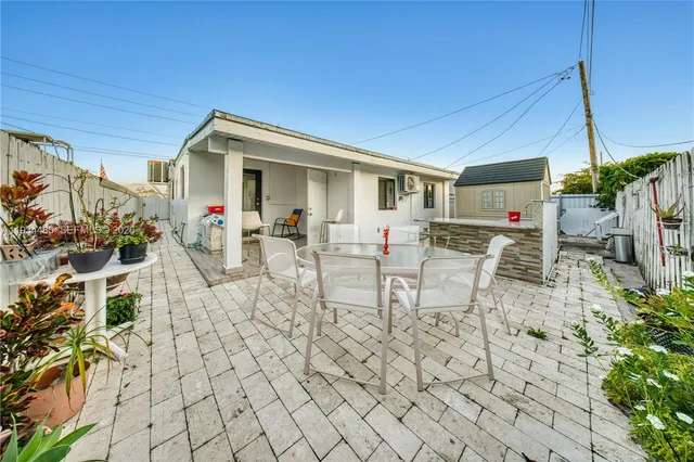 a view of a patio with table and chairs potted plants and floor to ceiling window and potted plants
