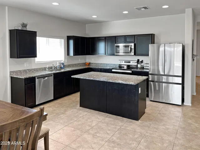 a kitchen with stainless steel appliances granite countertop a stove a sink dishwasher a refrigerator and a microwave