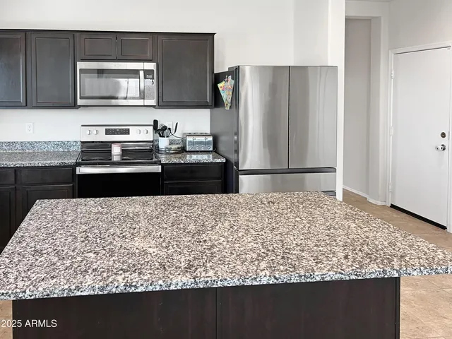 a kitchen with kitchen island sink and refrigerator