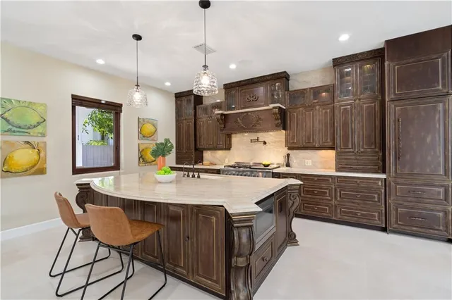 a kitchen with kitchen island granite countertop a sink a center island and stainless steel appliances