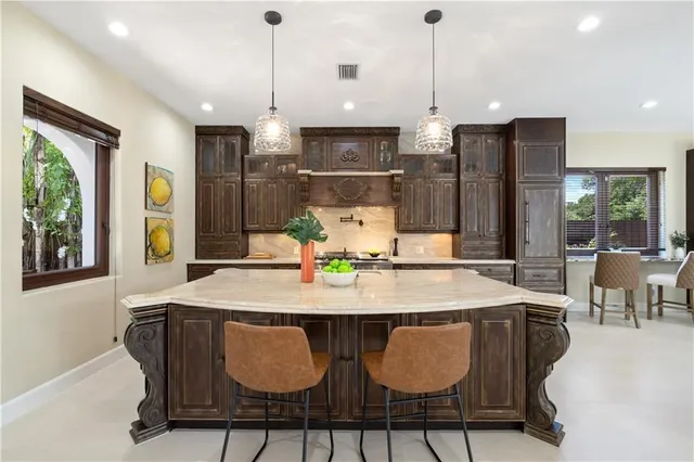 a kitchen with stainless steel appliances granite countertop a table chairs and a refrigerator